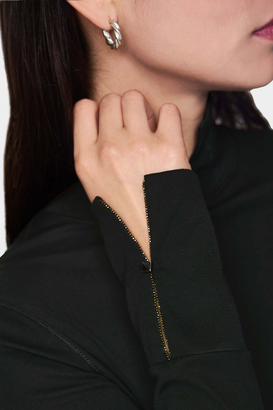Col roulé ajusté avec détail de fermeture zippée discrète sur le poignet, porté par une femme au style élégant.