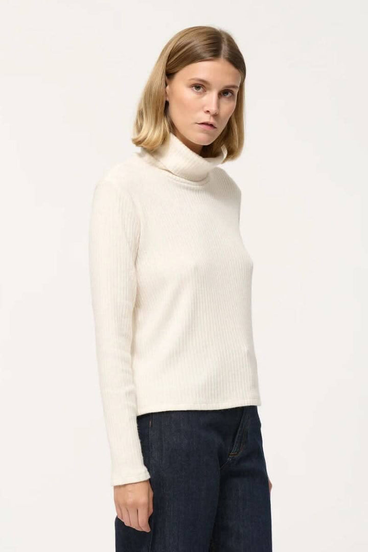 Col roulé côtelé en jersey crème, manches longues et style décontracté, parfait pour superposer.