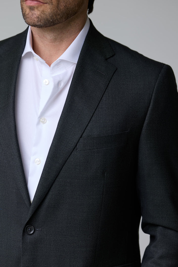 Homme portant un complet classique deux pièces avec veston noir et chemise blanche, idéal pour les occasions formelles.