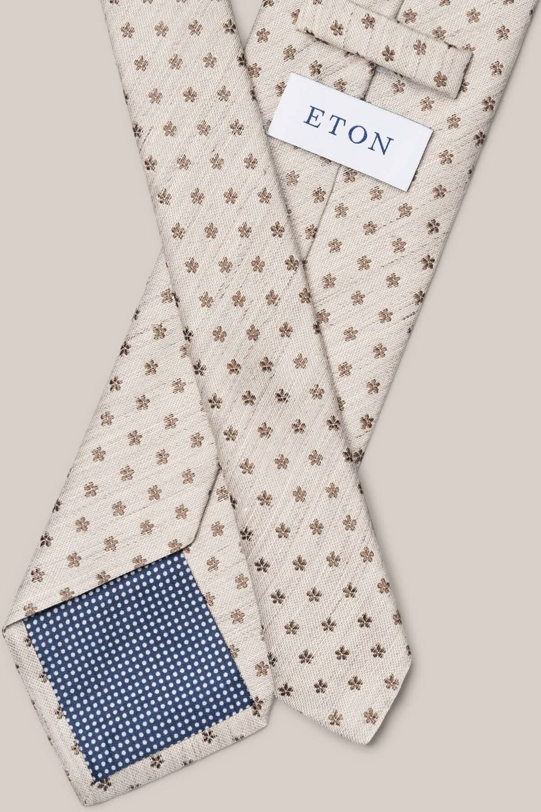 Cravate en lin et soie beige à motif floral brun, étiquette ETON, doublure bleu à pois.