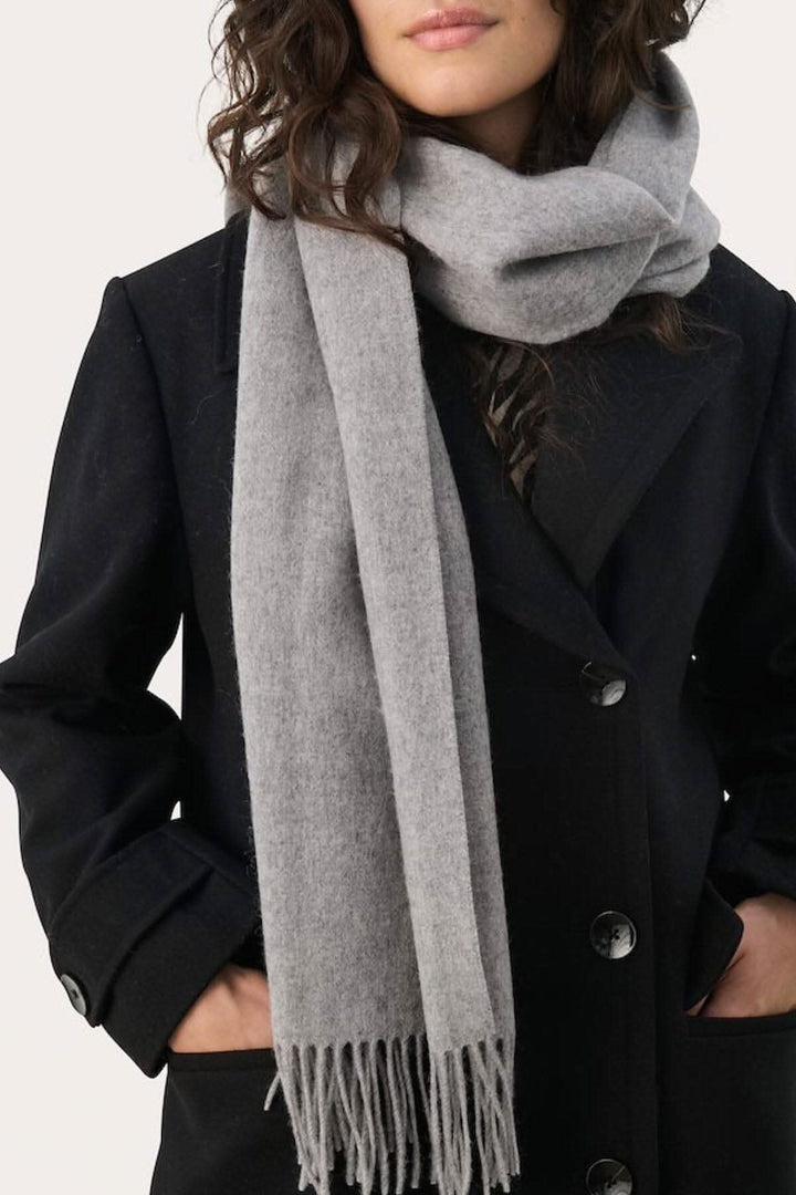 Foulard en laine Kitha gris porté avec un manteau noir, ajoutant chaleur et style aux tenues d&