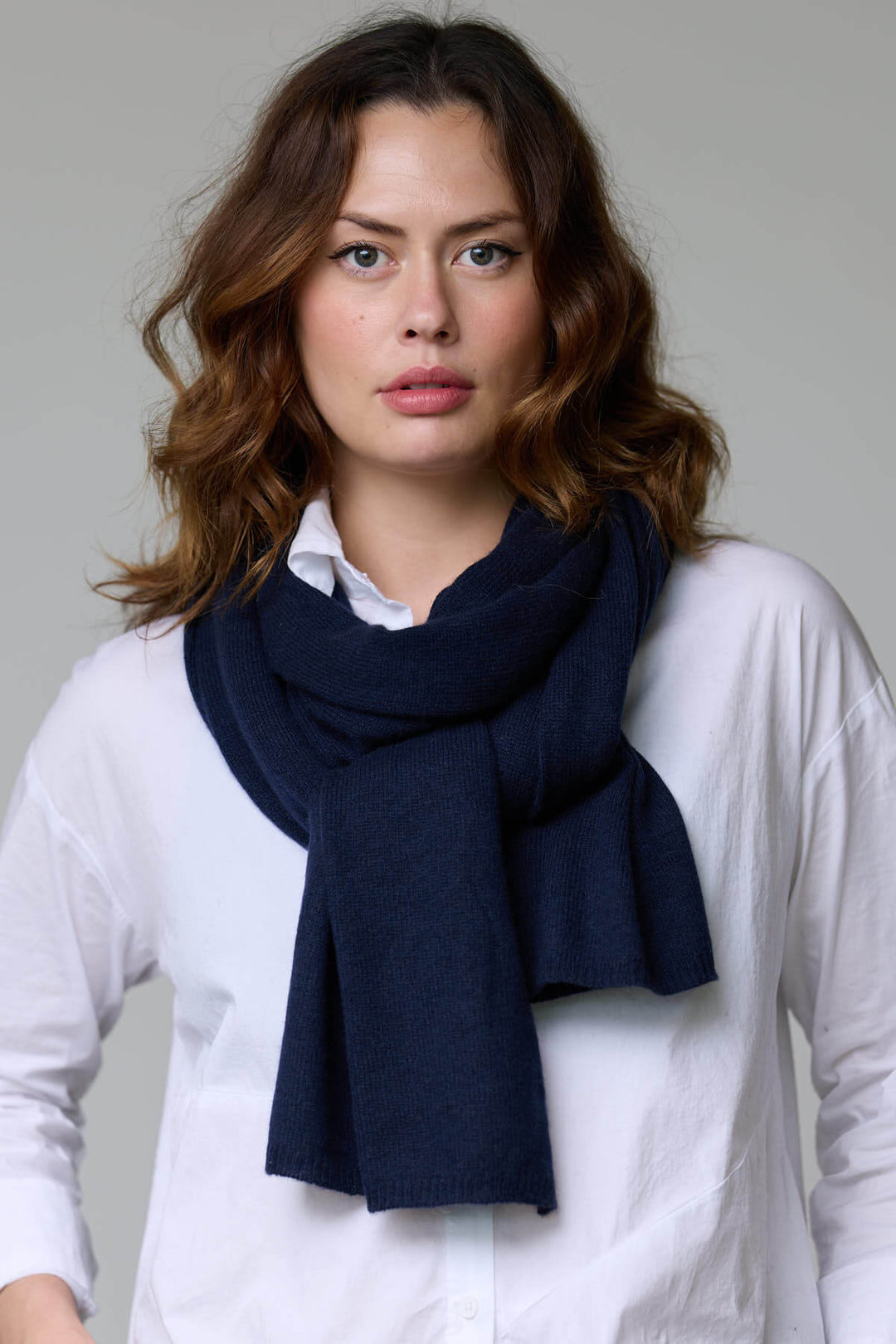 Femme portant un foulard en laine bleu marine avec une texture douce et moelleuse, idéal pour les tenues automnales et hivernales.