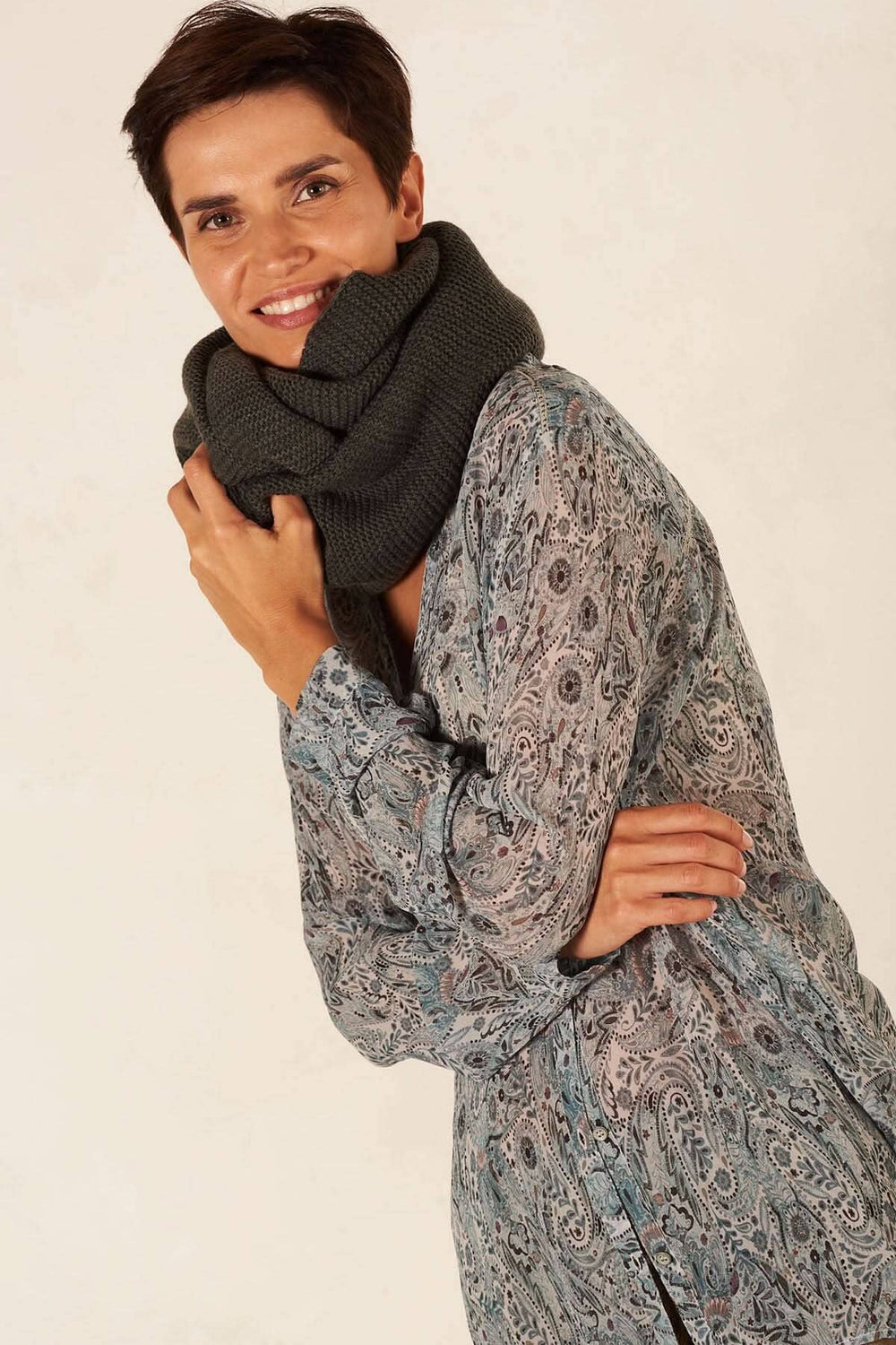 Foulard en tricot ample et chaud porté par une femme souriante en tenue élégante.