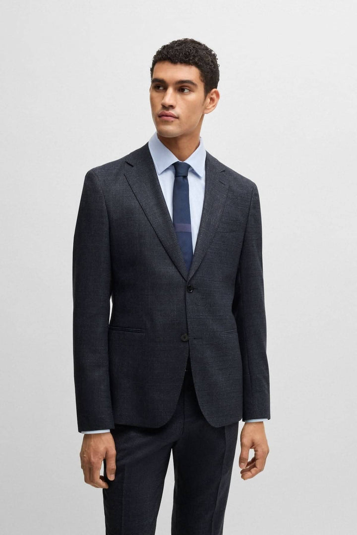 Homme en costume BOSS deux pièces, avec micro motif, ajusté et moderne, porté avec une chemise et une cravate.