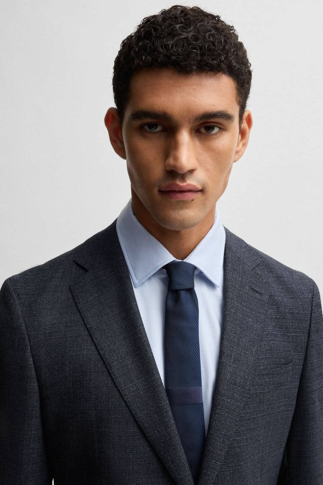 Homme portant un costume BOSS moderne en laine stretch avec cravate, idéal pour les occasions formelles.