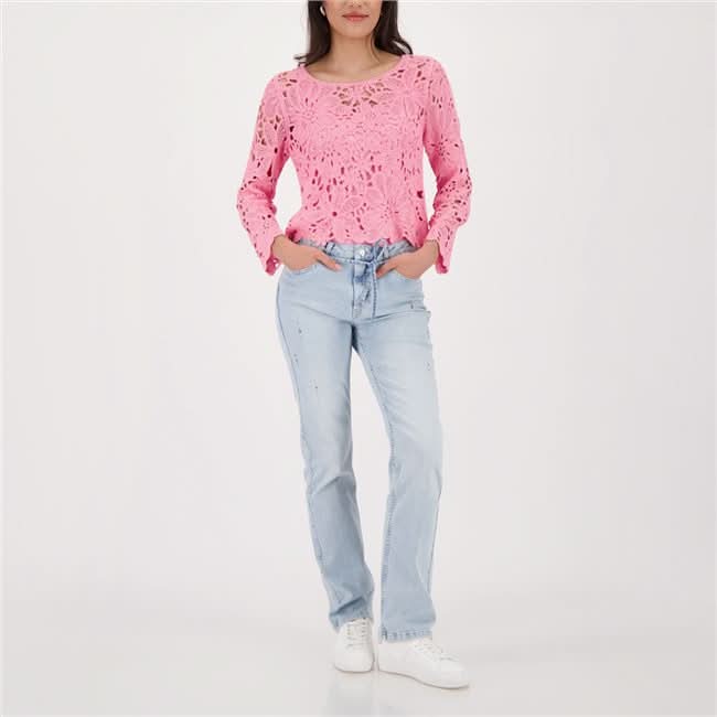 Femme portant un haut en tricot ajouré rose avec motif floral, assorti à un jean décontracté.