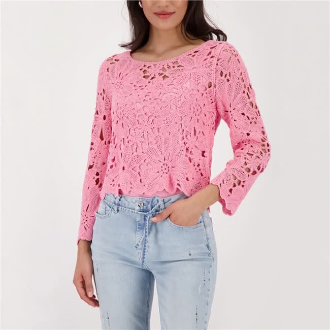 Haut en tricot ajouré rose à motif floral porté avec un jean, coupe légèrement ajustée, look moderne et féminin.