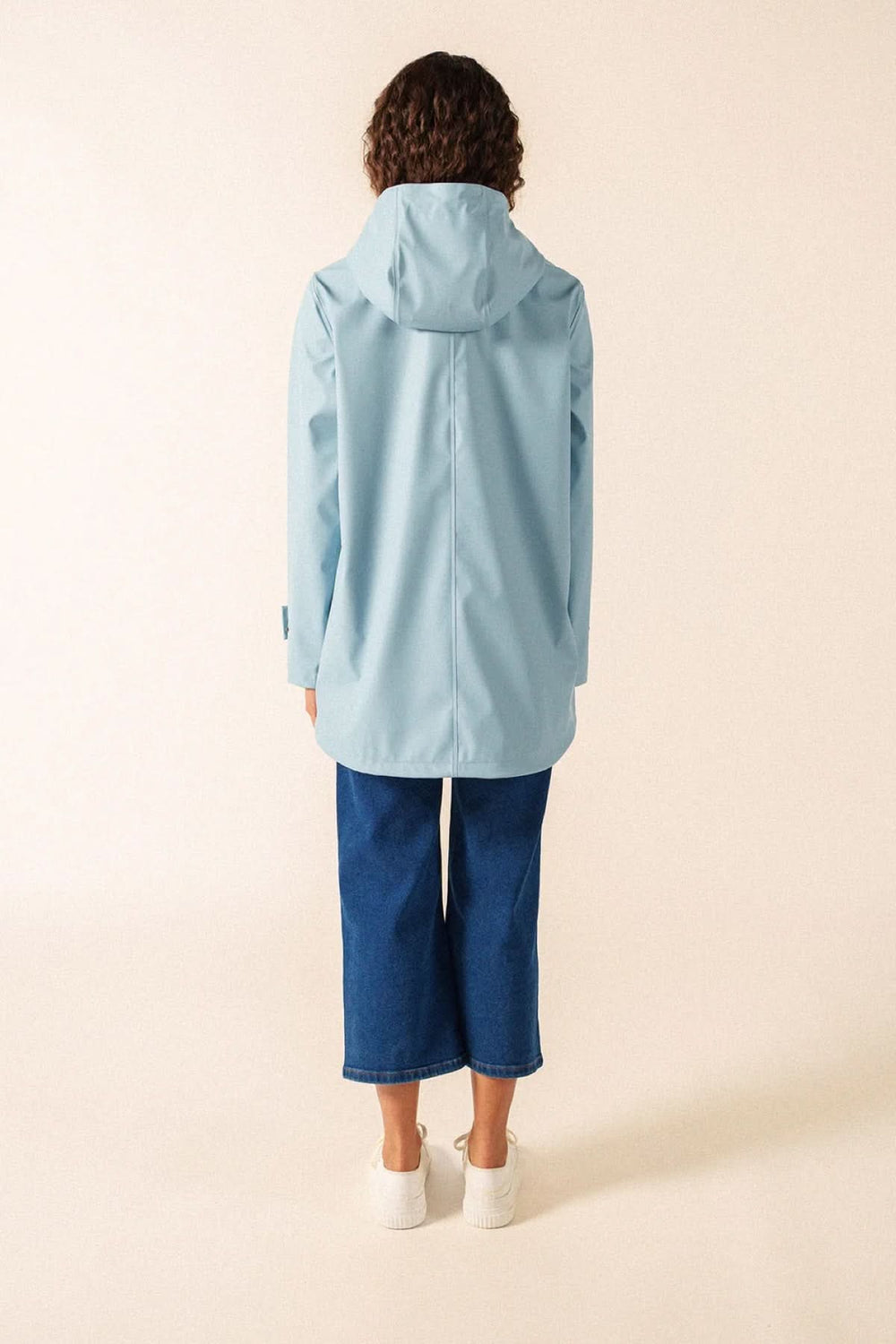 Femme portant un imperméable bleu clair Imperméable STE GAIA, ciré waterproof avec coutures soudées, idéal pour printemps et météo changeante.