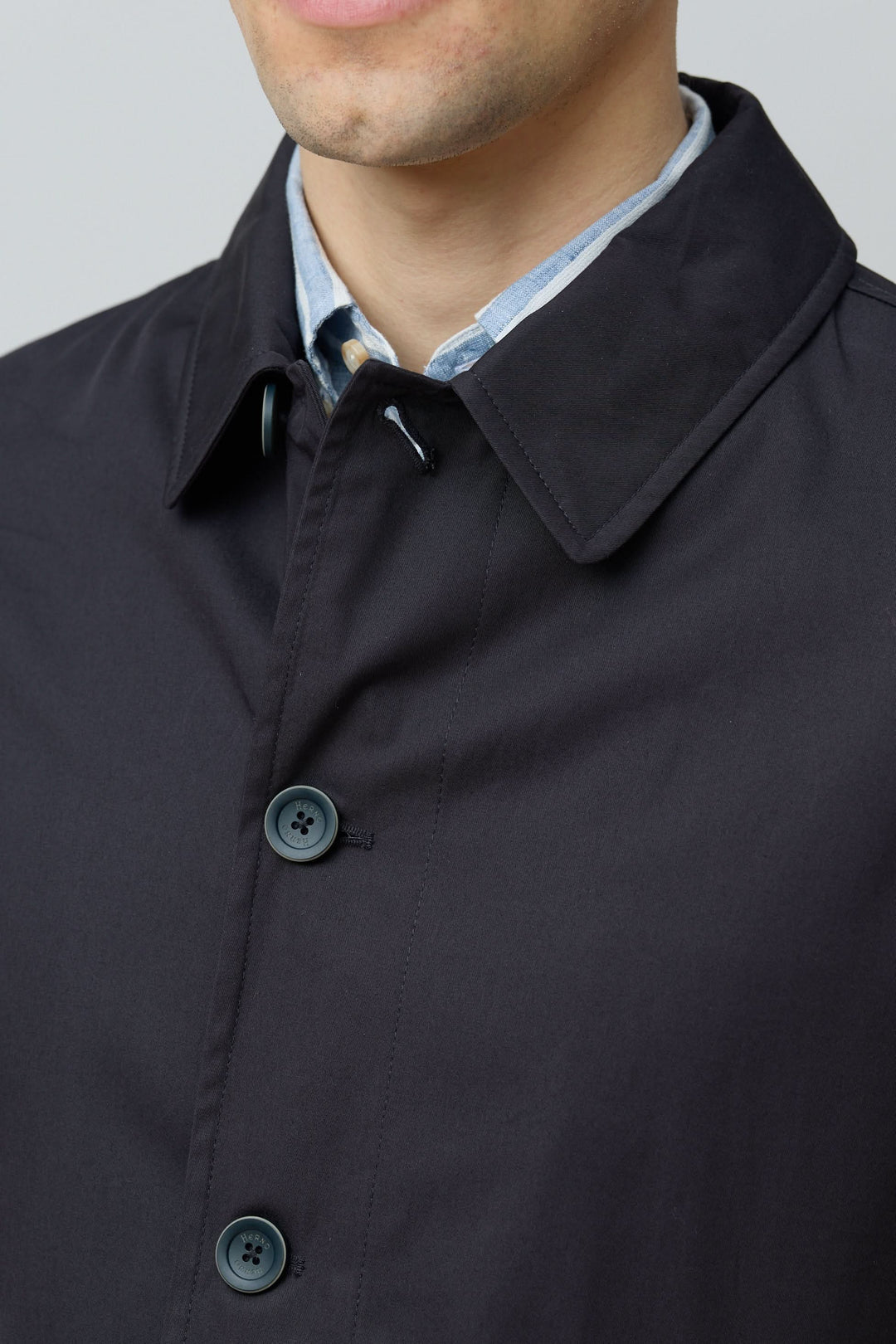Homme portant un imperméable en gabardine de coton avec col chemise, élégance urbaine et fonctionnalité par Herno – Officina Tessile.