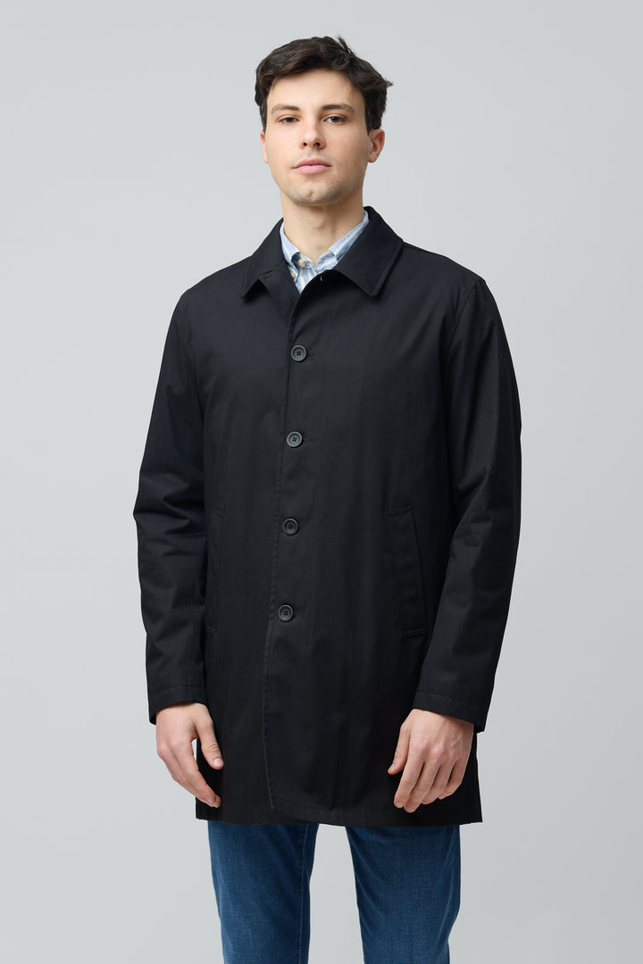 Homme portant un imperméable en gabardine de coton noir avec coupe droite et col chemise, idéal pour un look urbain élégant.