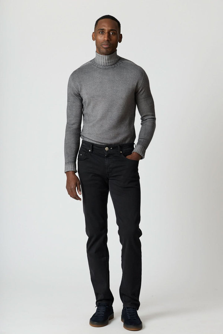 Homme portant Jean 5 poches stretch coupe moderne noir avec pull gris et sneakers noires.