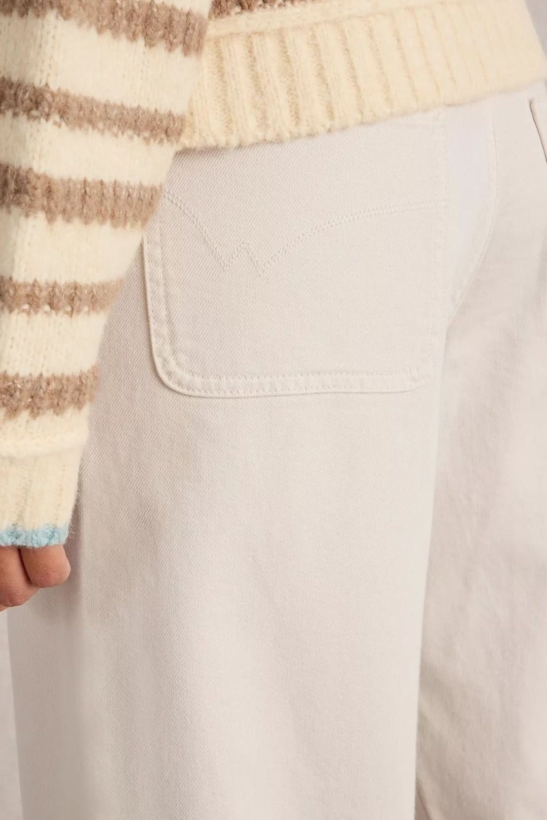 Jean Tia court à jambes larges, gros plan sur poche plaquée et pull rayé crème.