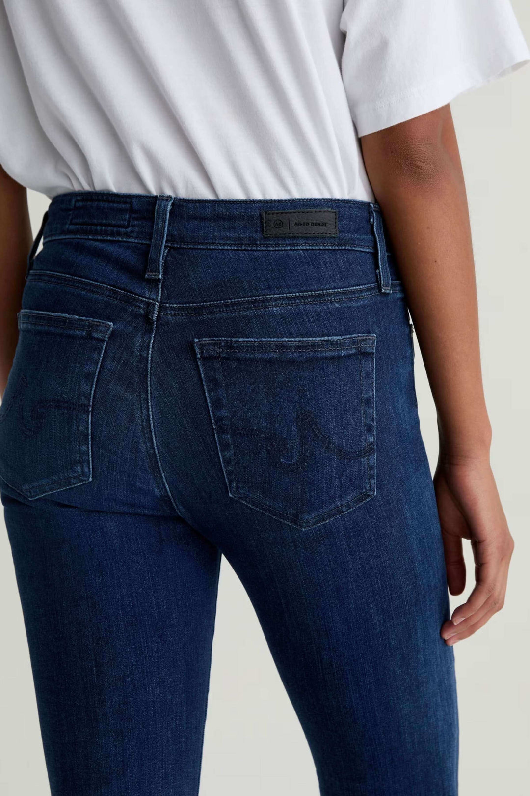 Jean ajusté à taille mi-haute en denim extensible, vue arrière, porté avec un t-shirt blanc.