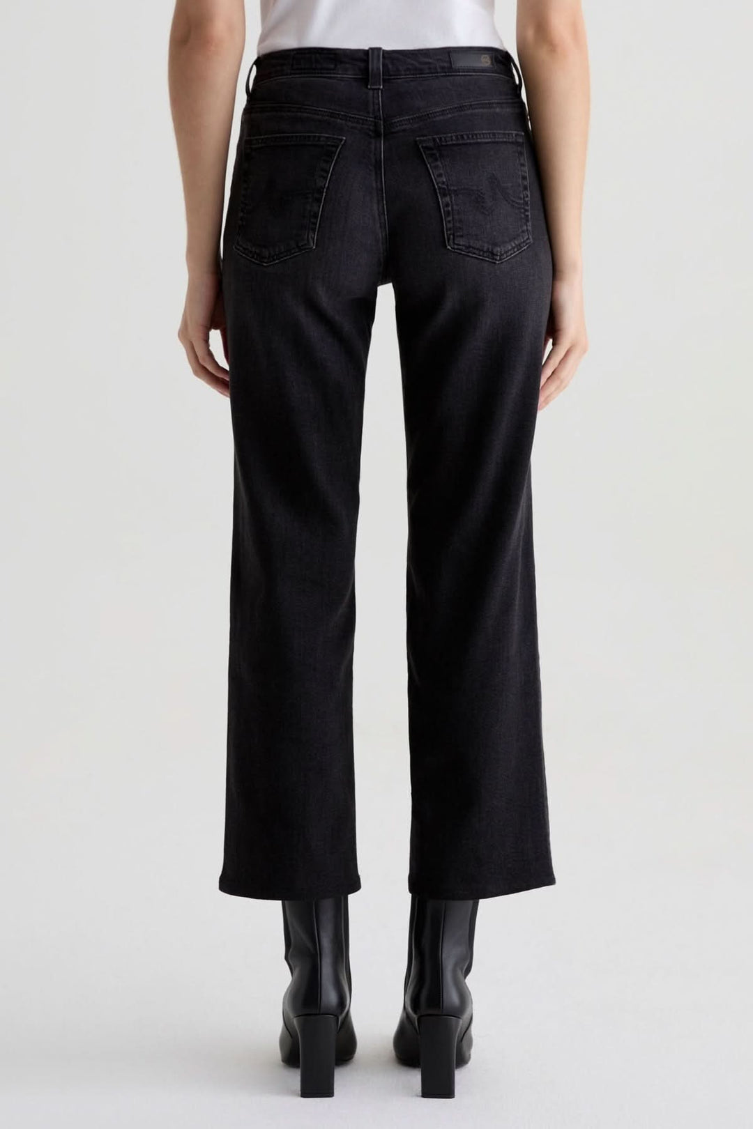 Personne portant un jean à coupe droite noir délavé avec des bottillons, vue arrière