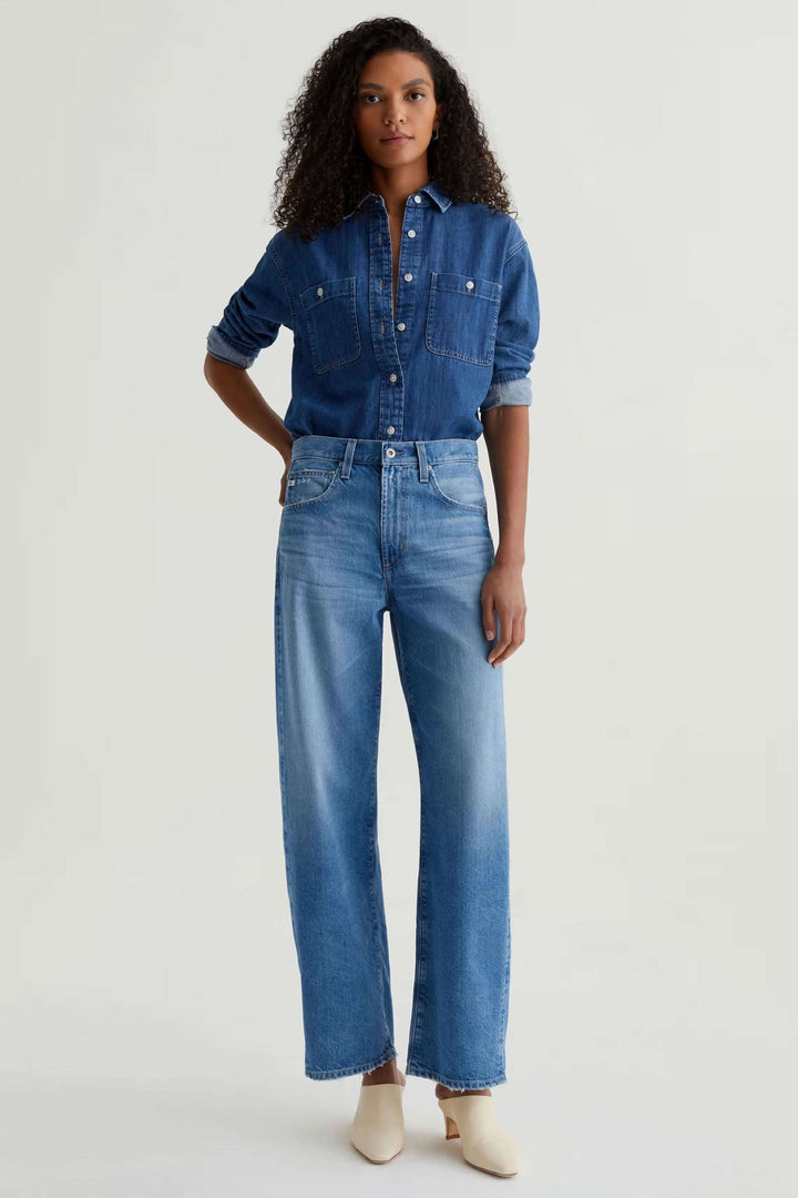 Jean droit à jambe large porté avec une chemise en denim pour un look moderne et décontracté.