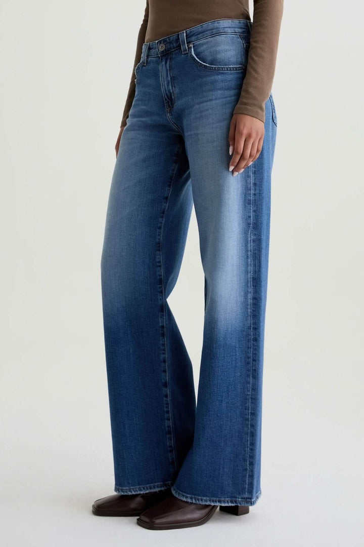 Jean à jambe large, coupe ample et délavage moyen, porté avec élégance pour un style moderne et fluide.