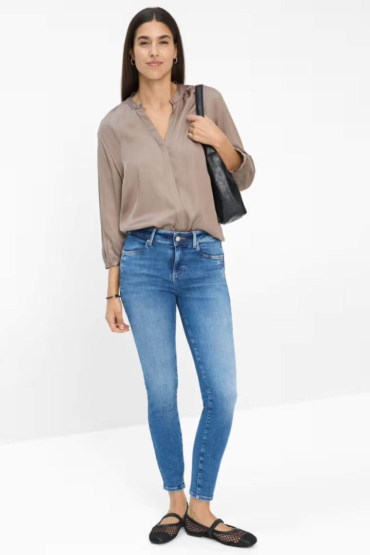 Jean skinny de style Ana bleu clair avec blouse fluide, silhouette féminine élégante.