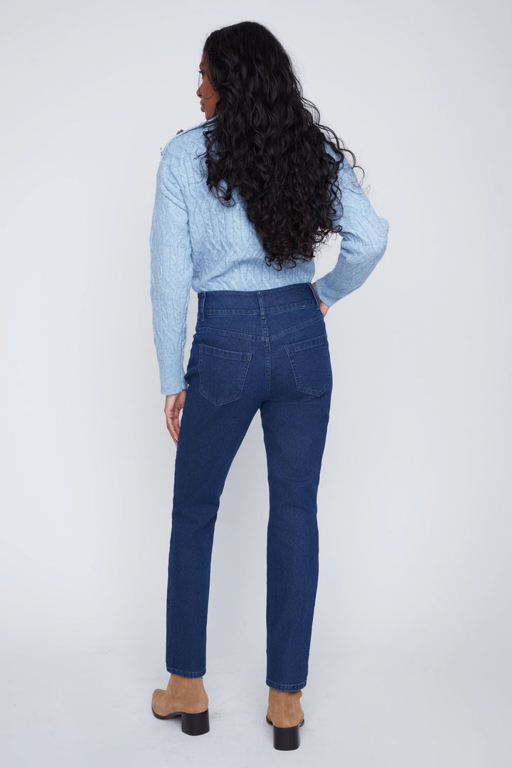 Jean taille haute bleu avec boutons apparents et coupe droite, porté avec un chandail bleu et des bottines beiges.