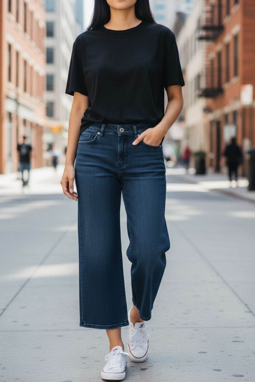 Jeans jambe évasée en denim bleu, style décontracté avec taille régulière, porté avec un t-shirt noir, idéal pour un look moderne.