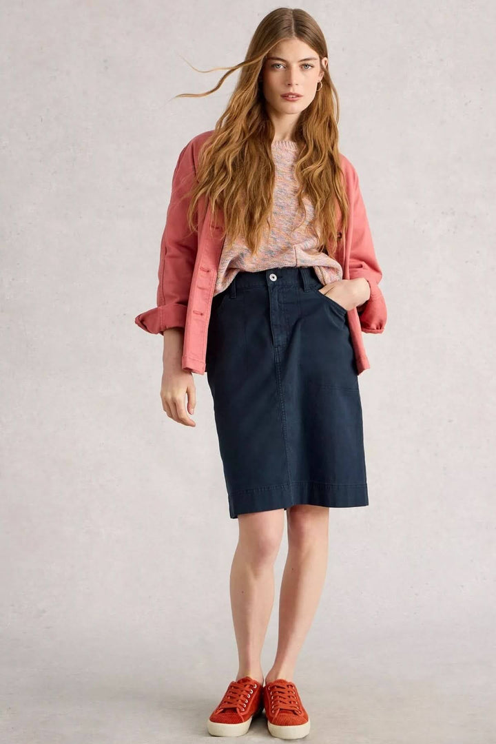 Femme portant la Jupe Tia bleu marine à taille haute, associée à un pull coloré et des baskets pour un look urbain chic.