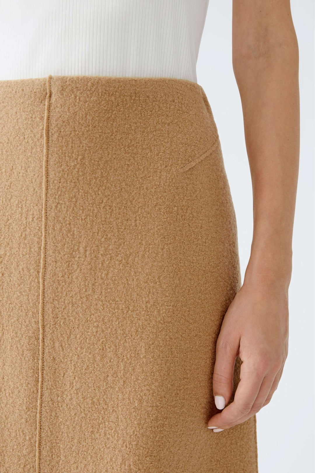 Jupe courte en lainage, taille haute avec tissu doux et coupe droite, montrée portée avec haut blanc.