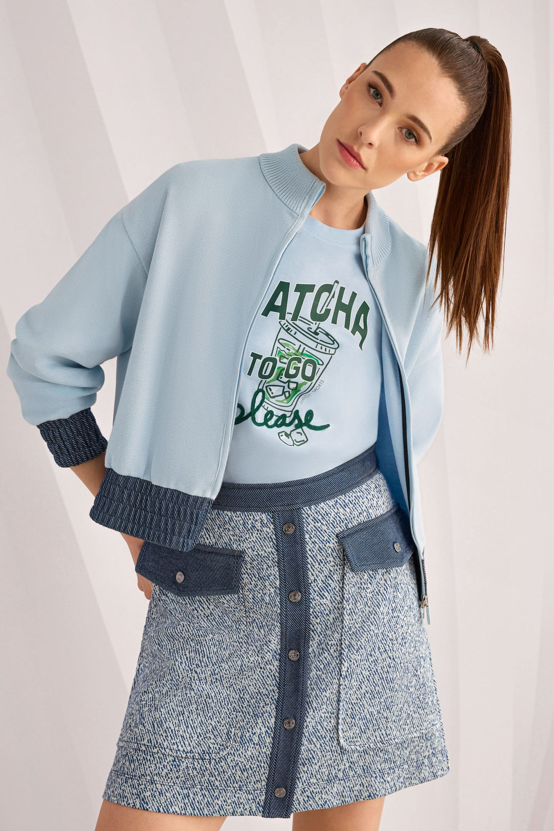 Femme portant une jupe courte en viscose extensible avec une veste bleue et un t-shirt, vue avant en intérieur.