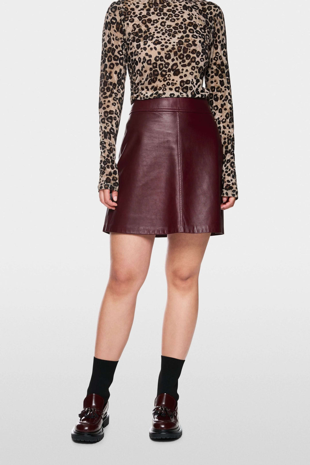 Jupe en cuir trapèze bordeaux, coupe flatteuse mi-haute, idéale pour un look chic avec col roulé ou décontracté avec t-shirt.
