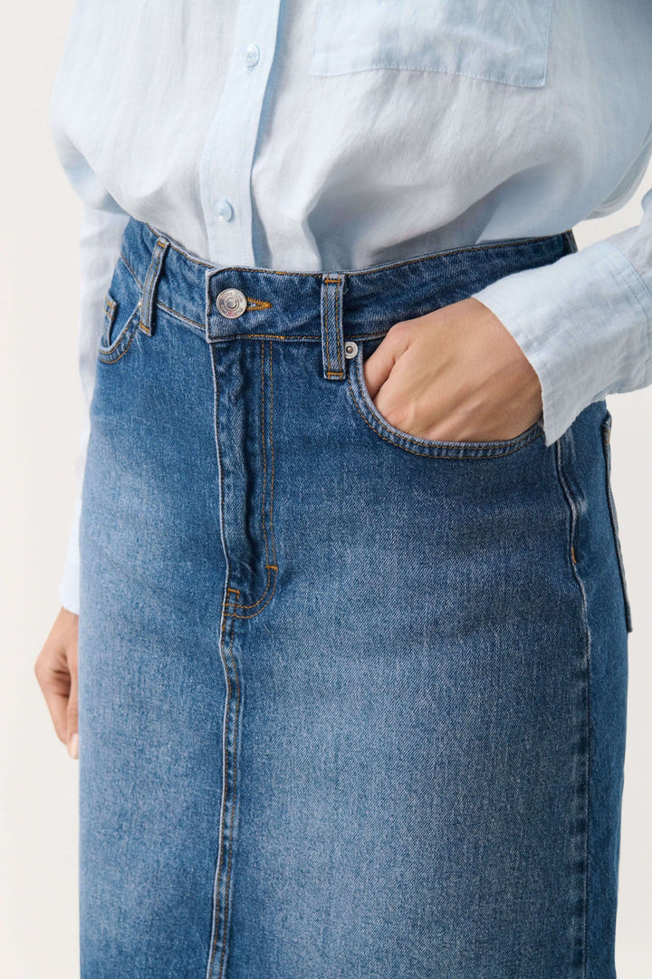 Jupe en denim Leja avec coupe flatteuse, poches pratiques et taille mi-haute, portée avec un haut léger.