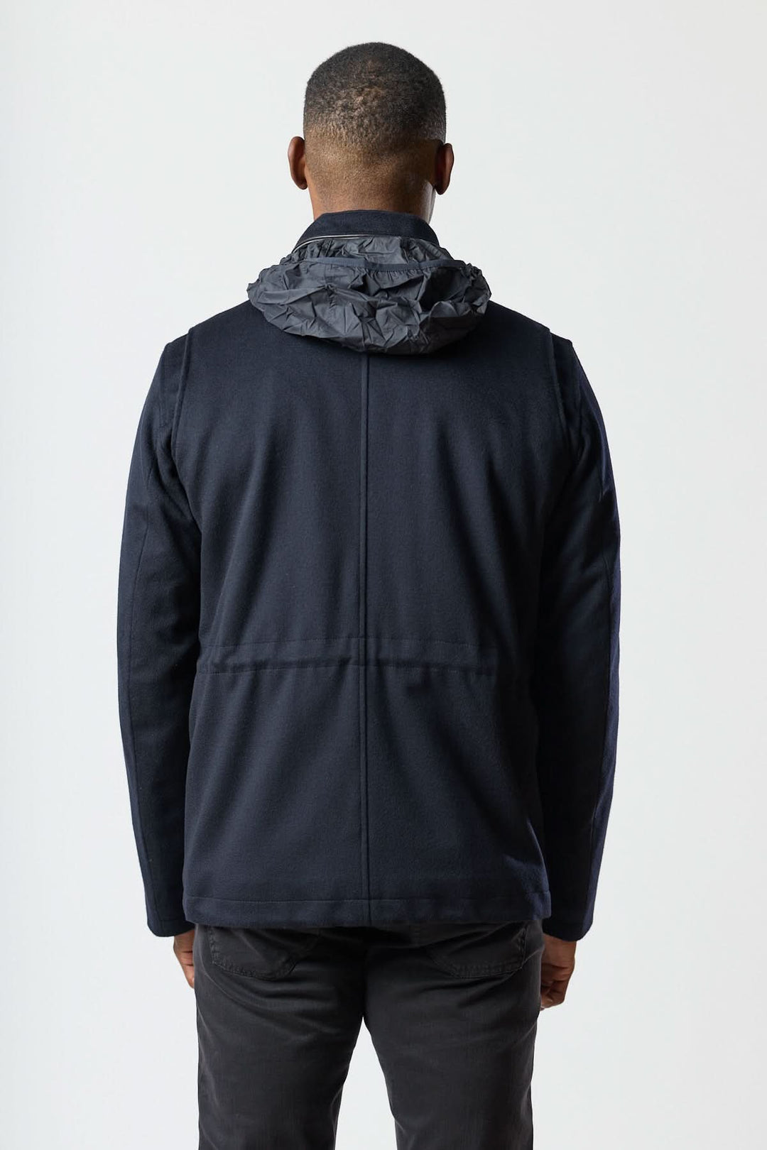 Dos du manteau en laine à quatre poches avec capuche légère, style veste structurée, parfait pour un look smart-casual élégant.