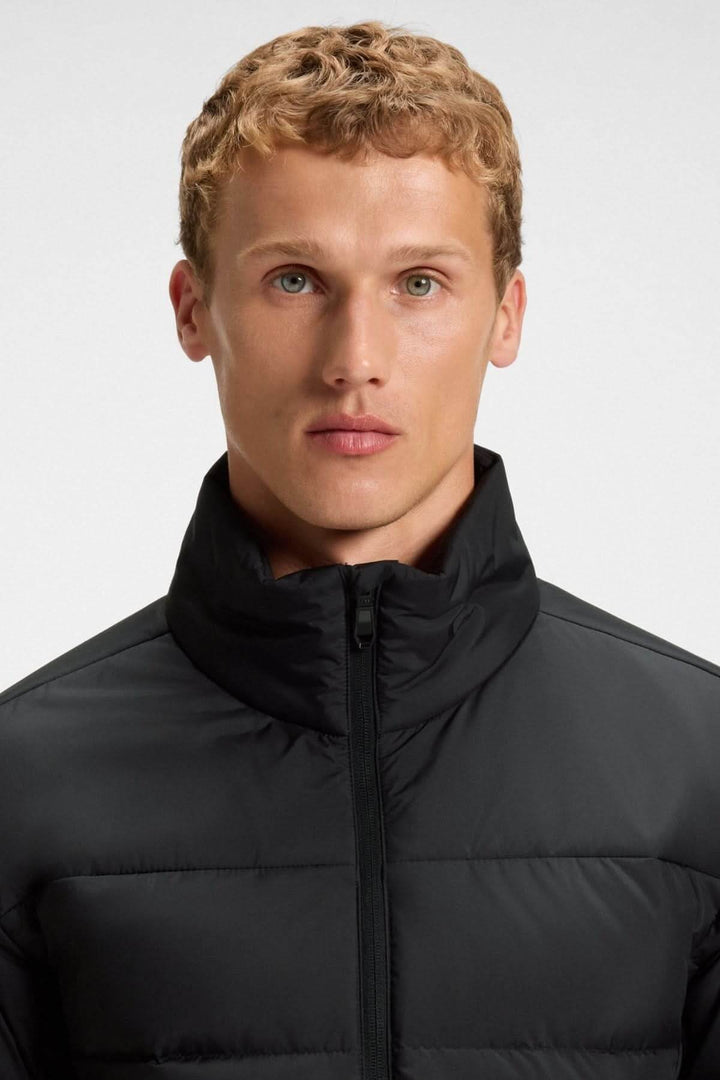Homme portant un manteau matelassé déperlant en duvet avec poche sur la manche de BOSS, idéal pour la mi-saison.