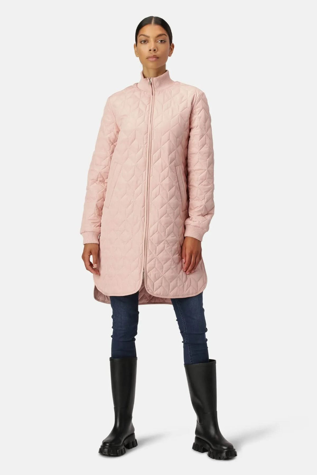 Manteau matelassé long à col montant rose porté avec un jean ajusté et des bottes hautes, style élégant et moderne.