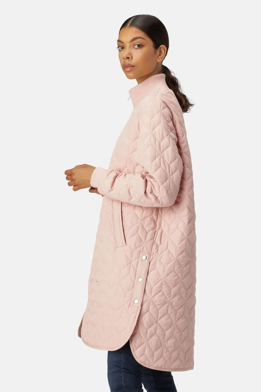 Femme portant un manteau matelassé long à col montant rose, avec motifs géométriques. Style moderne et urbain.