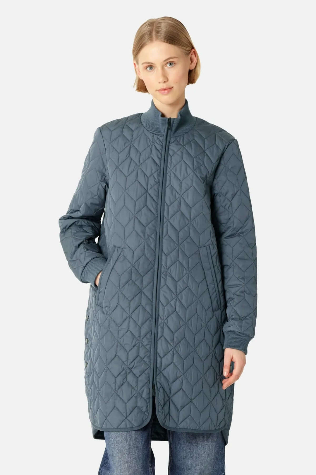 Femme portant un manteau matelassé long à col montant avec motifs géométriques et poches latérales, style urbain et moderne.