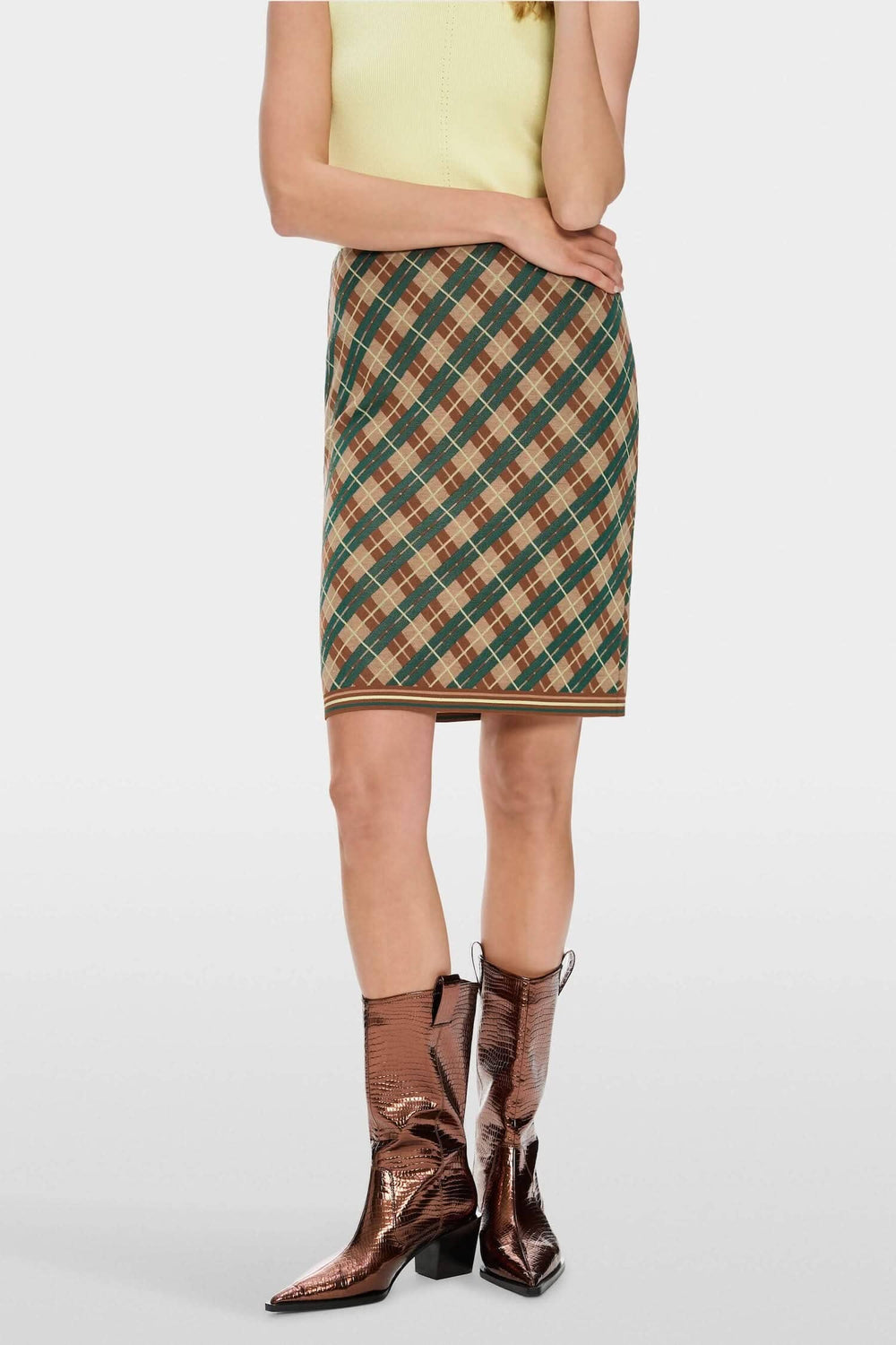 Mini-jupe à carreaux argyle avec ceinture élastiquée, portée avec des bottes brillantes.