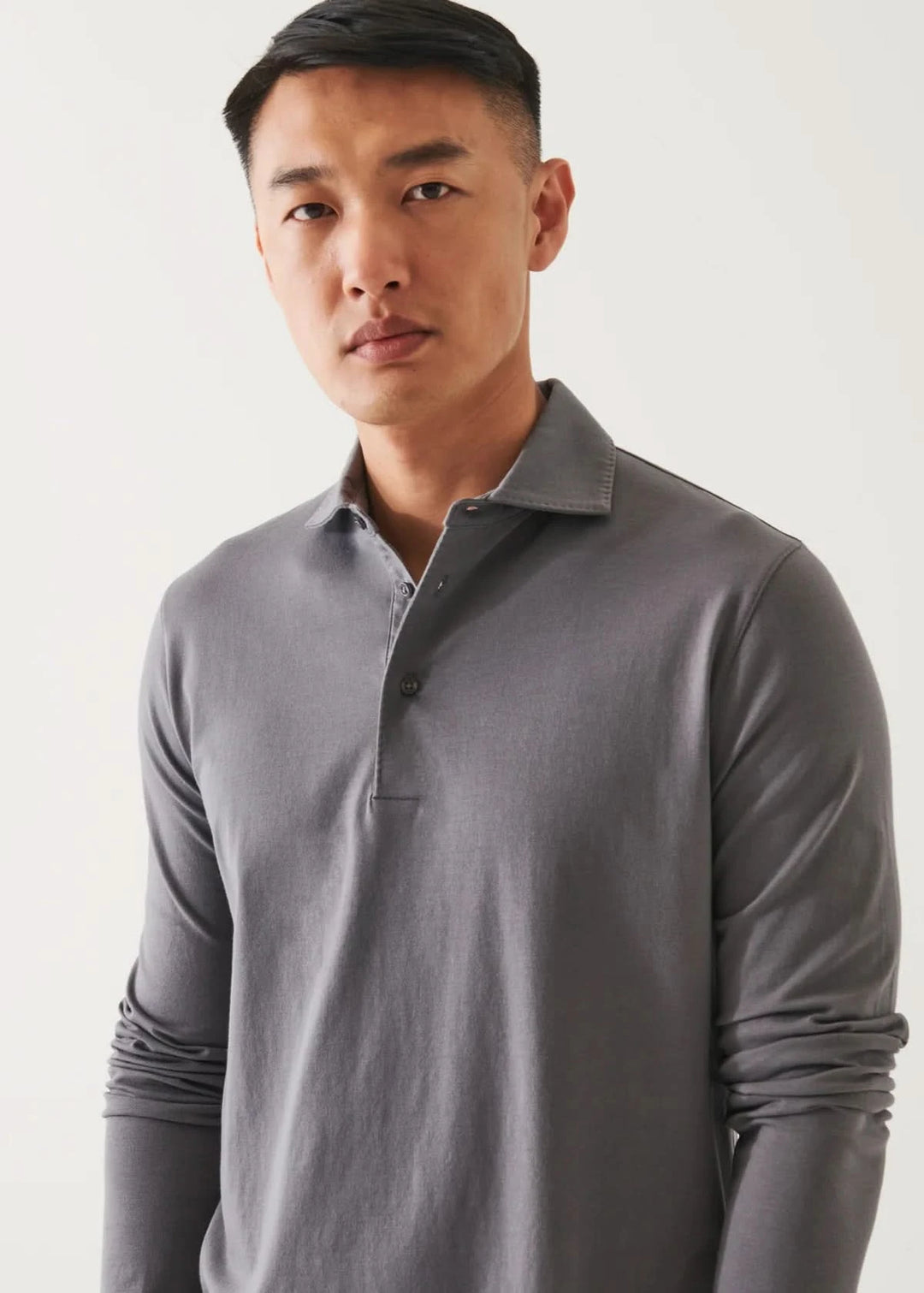 Homme portant un polo en coton stretch à manches longues de couleur grise, look décontracté et élégant.