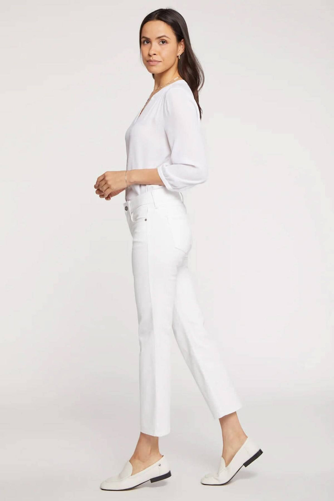 Femme en pantalon Marilyn blanc, coupe classique, portée avec un haut blanc et des chaussures légères.