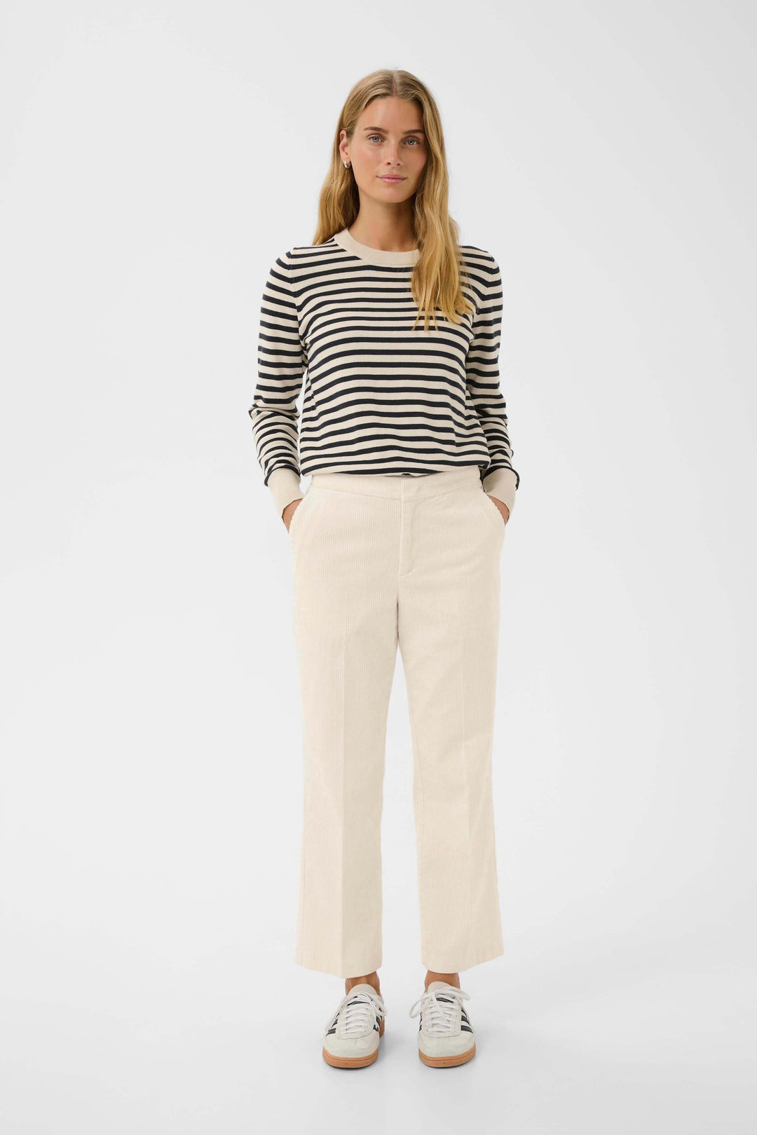 Femmes portant Pantalon Mishas en velours côtelé beige avec chandail rayé, look casual chic avec coupe droite et moderne.