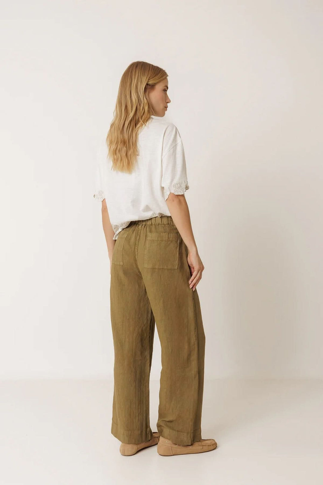 Femme portant un pantalon ample en lin à poches plaquées, vue de dos, harmonie avec un style décontracté et moderne.