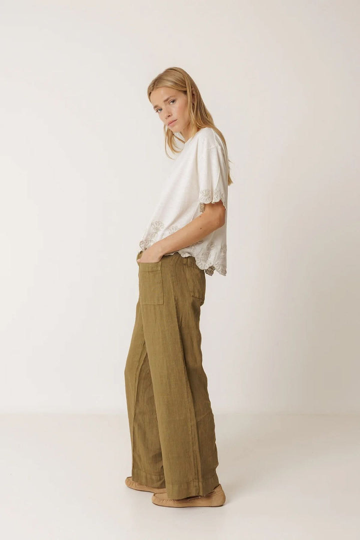 Femme portant un pantalon ample en lin à poches plaquées, style décontracté et moderne.