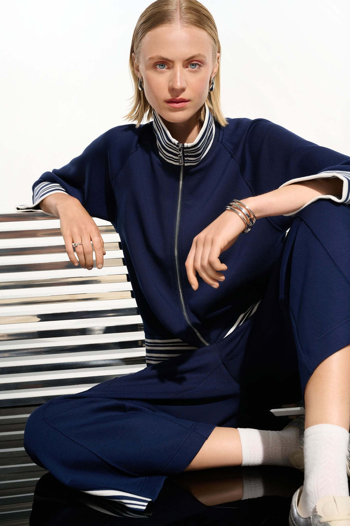 Pantalon athlétique à bandes contrastantes, coupe droite, style sportif chic avec confort, fente latérale, femme assise élégamment.