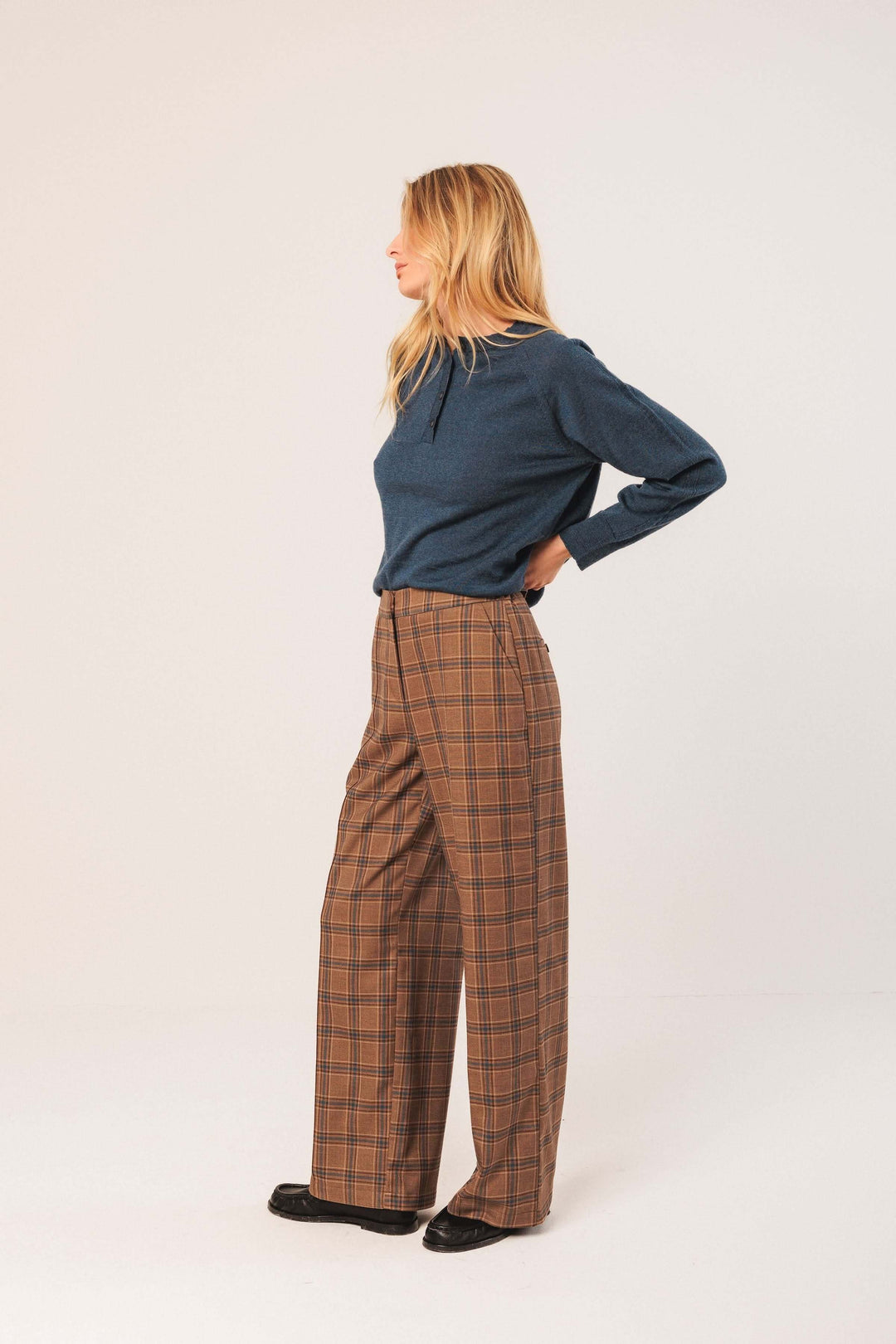 Femme portant un pantalon à carreaux à coupe large et fluide, idéal pour une tenue chic et moderne avec motif intemporel.