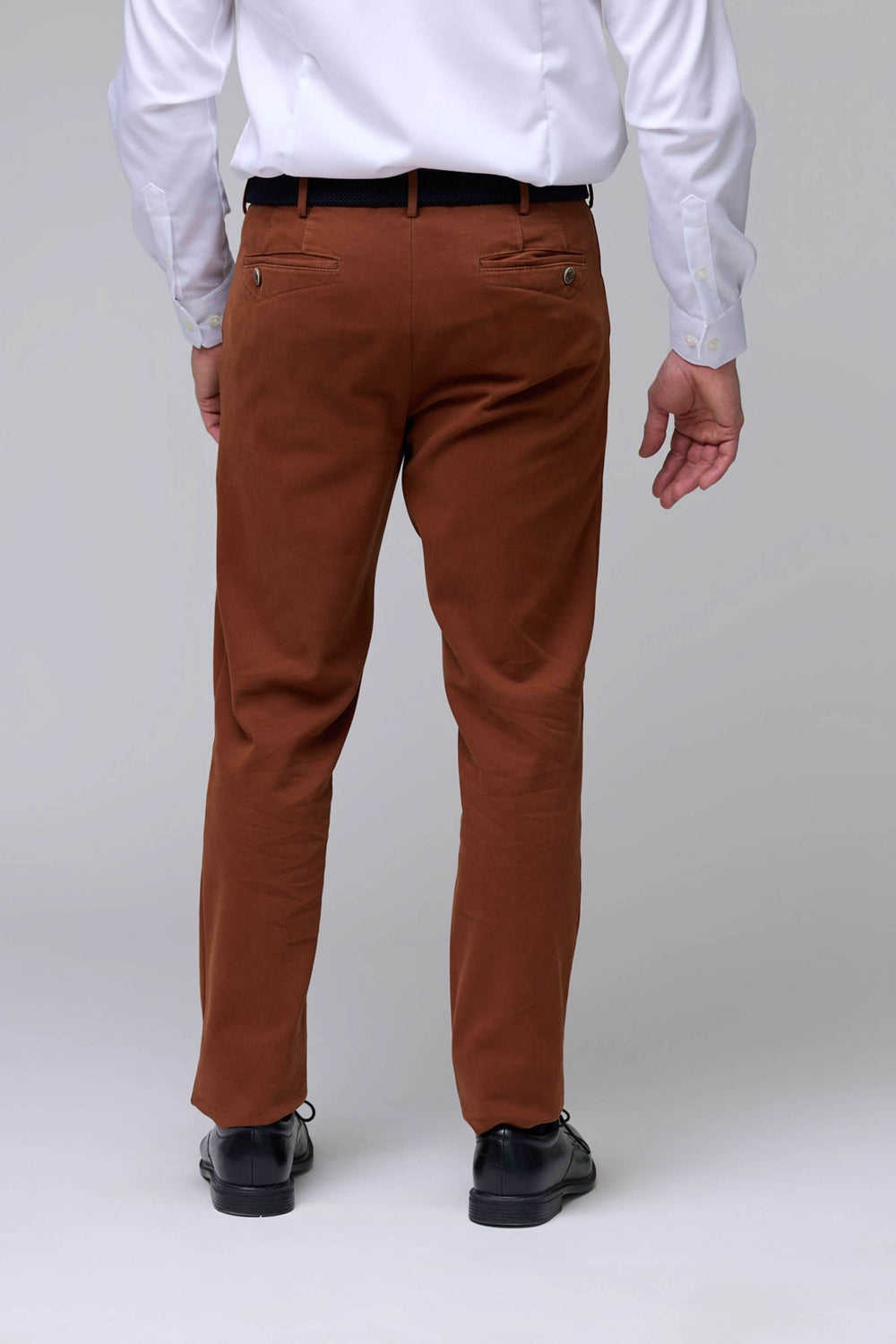 Vue de dos d'un homme portant un pantalon chino moderne marron avec chemise blanche.