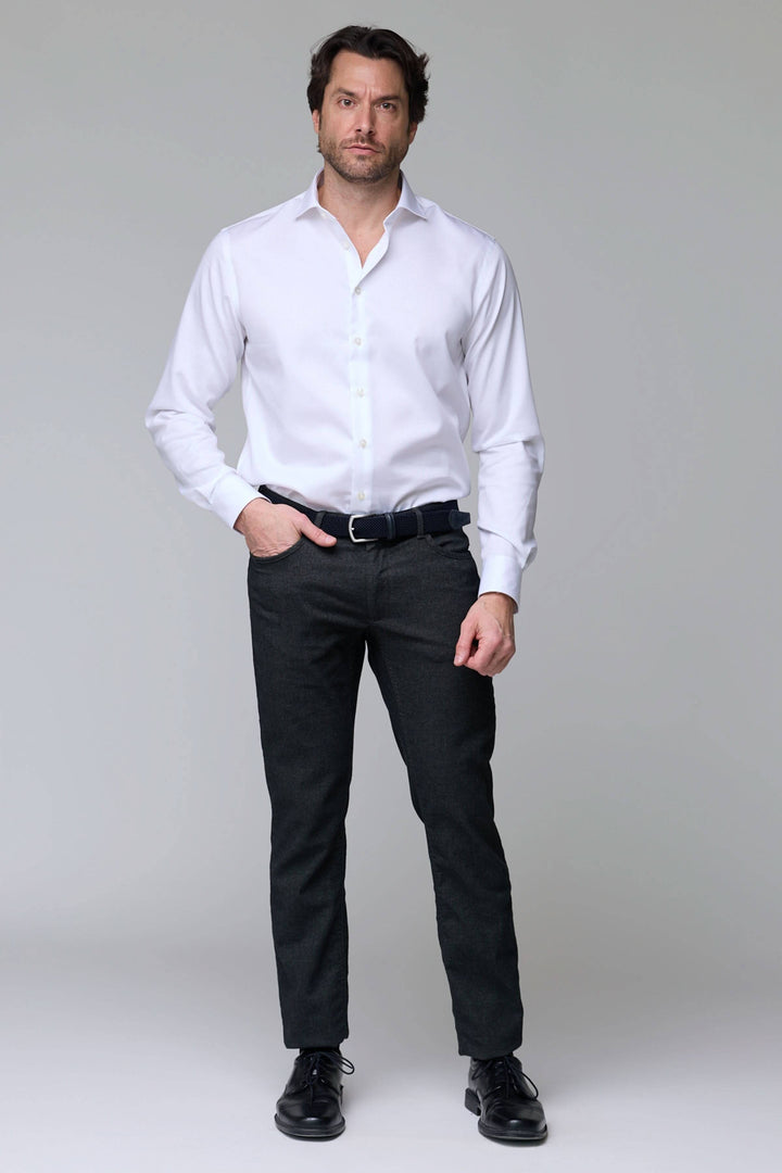 Homme portant un pantalon en laine extensible et une chemise blanche, coupe moderne et élégante, idéal pour le bureau.