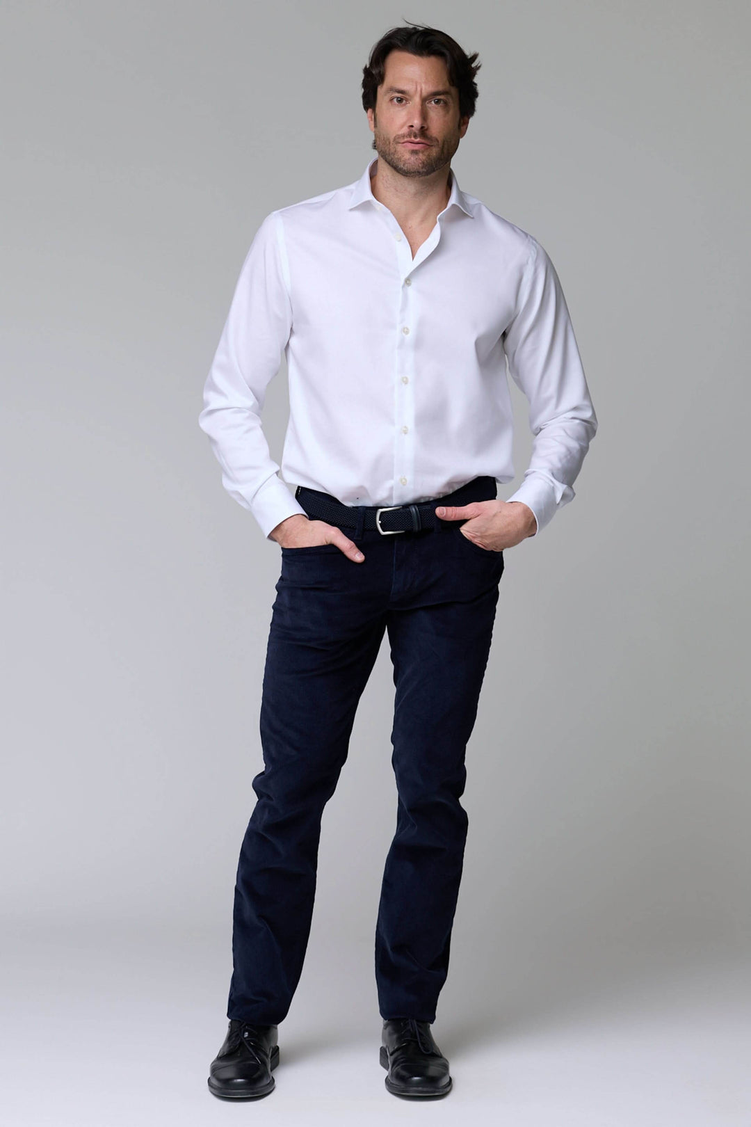 Homme portant un pantalon en velours côtelé bleu marine avec une chemise blanche, style élégant et décontracté.