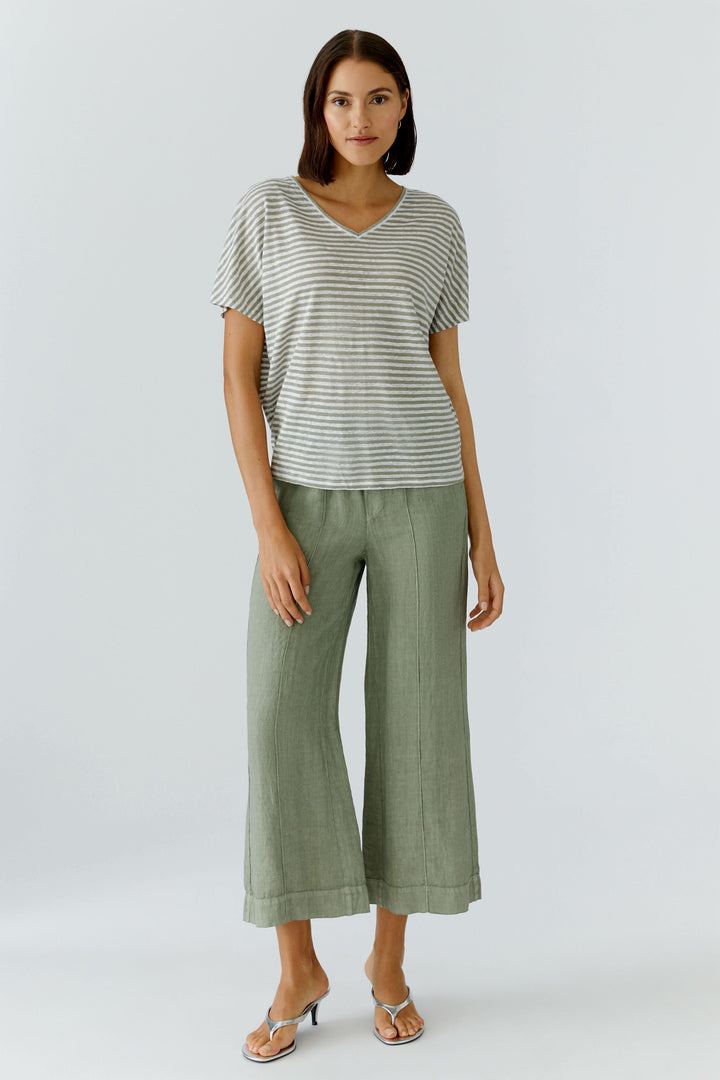 Femme portant un pantalon fluide en lin à jambe large avec un t-shirt rayé, parfait pour un look moderne et décontracté.