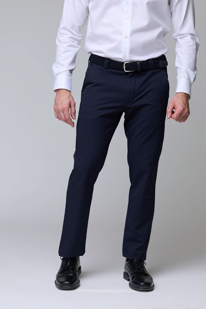 Homme portant un pantalon habillé extensible bleu marine avec chemise blanche, coupe droite et contemporaine pour un style professionnel.