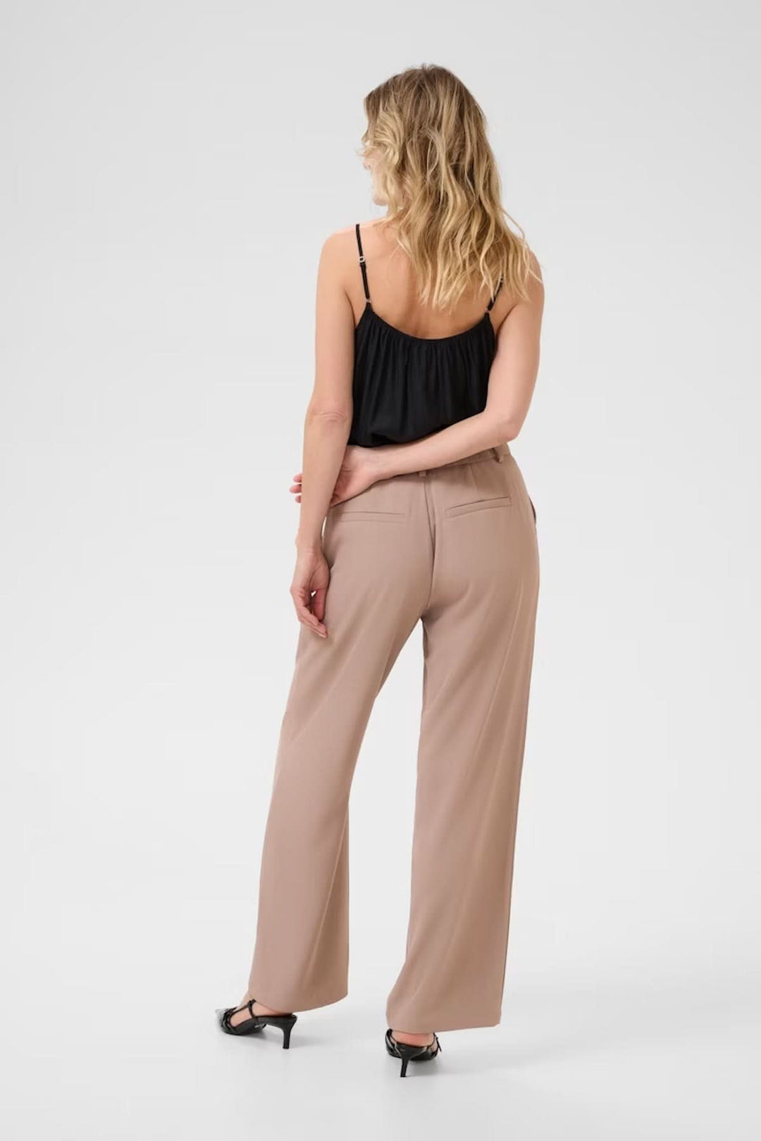 Femme portant un pantalon à jambe large beige avec coupe fluide et taille régulière, vue de dos, style élégant et professionnel.