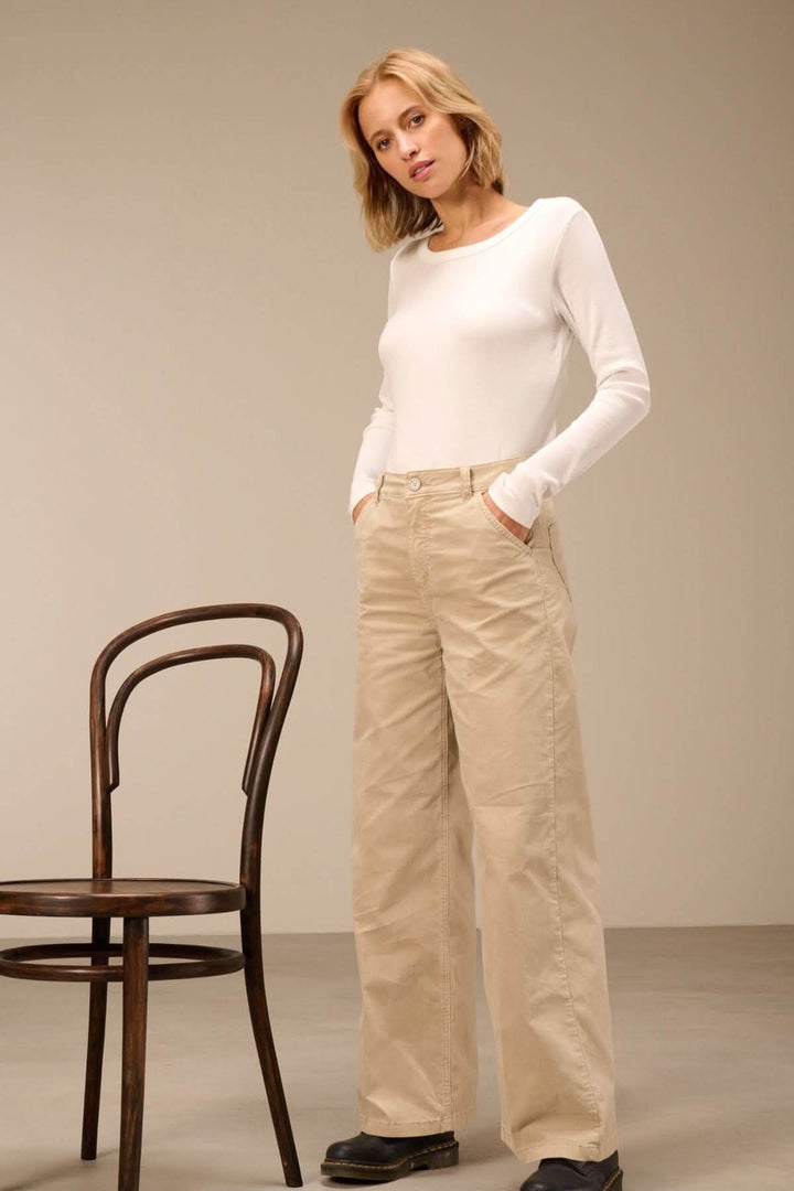 Femme portant un pantalon large taille haute avec chandail blanc, à côté d&