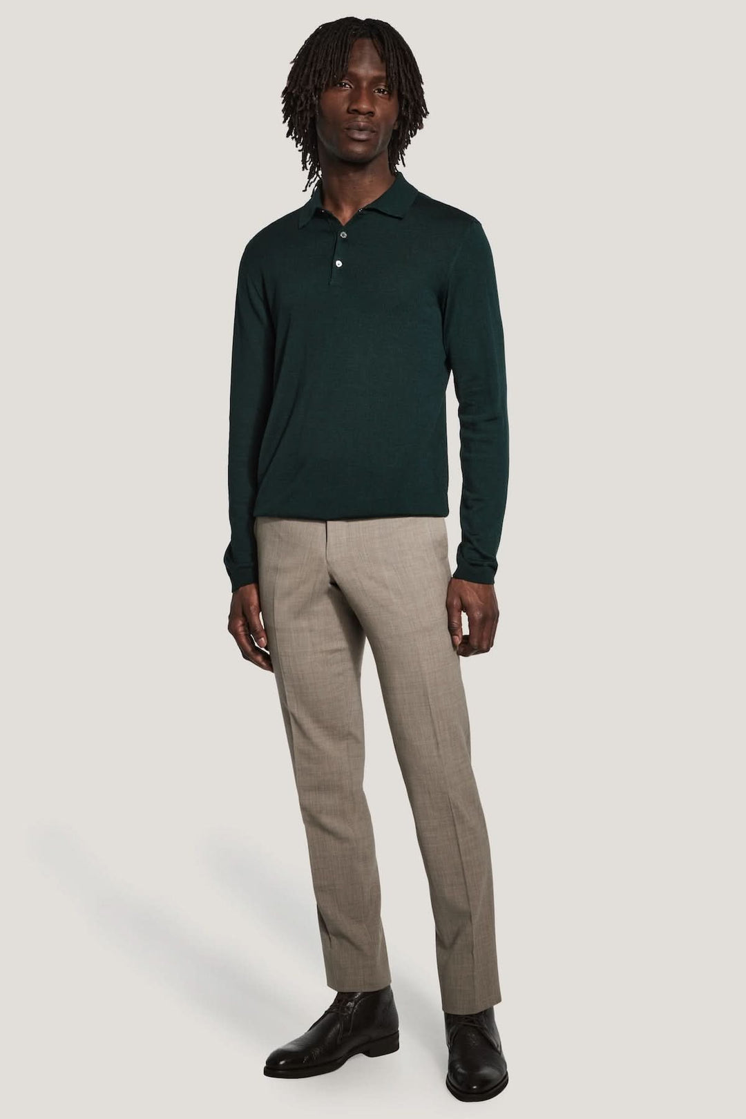 Polo manches longues en laine mérinos et soie, homme portant polo vert foncé et pantalon beige. Modes élégante et moderne.