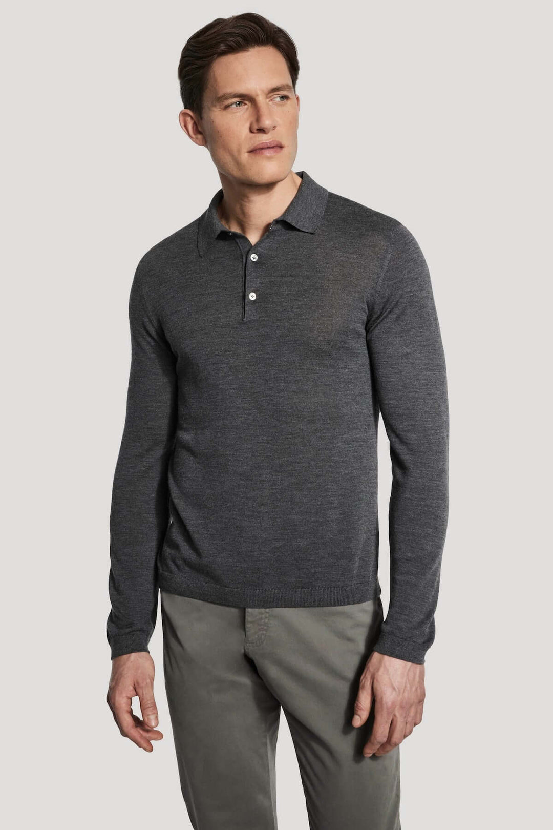 Homme portant un polo manches longues en laine mérinos et soie, couleur grise, tricoté maille fine pour un confort élégant et sophistiqué.